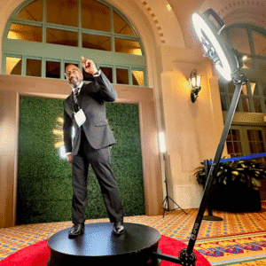 A man standing on a 360 photo booth also called the 360 video slowmo booth.