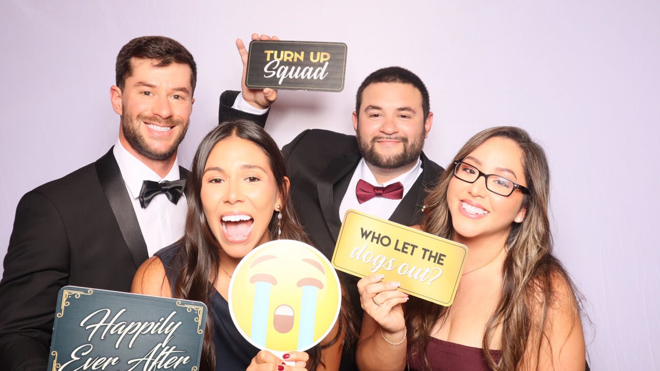 Family posing with props at a South Florida photo booth rental during a wedding