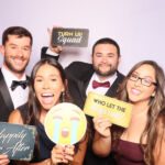 Family posing with props at a South Florida photo booth rental during a wedding