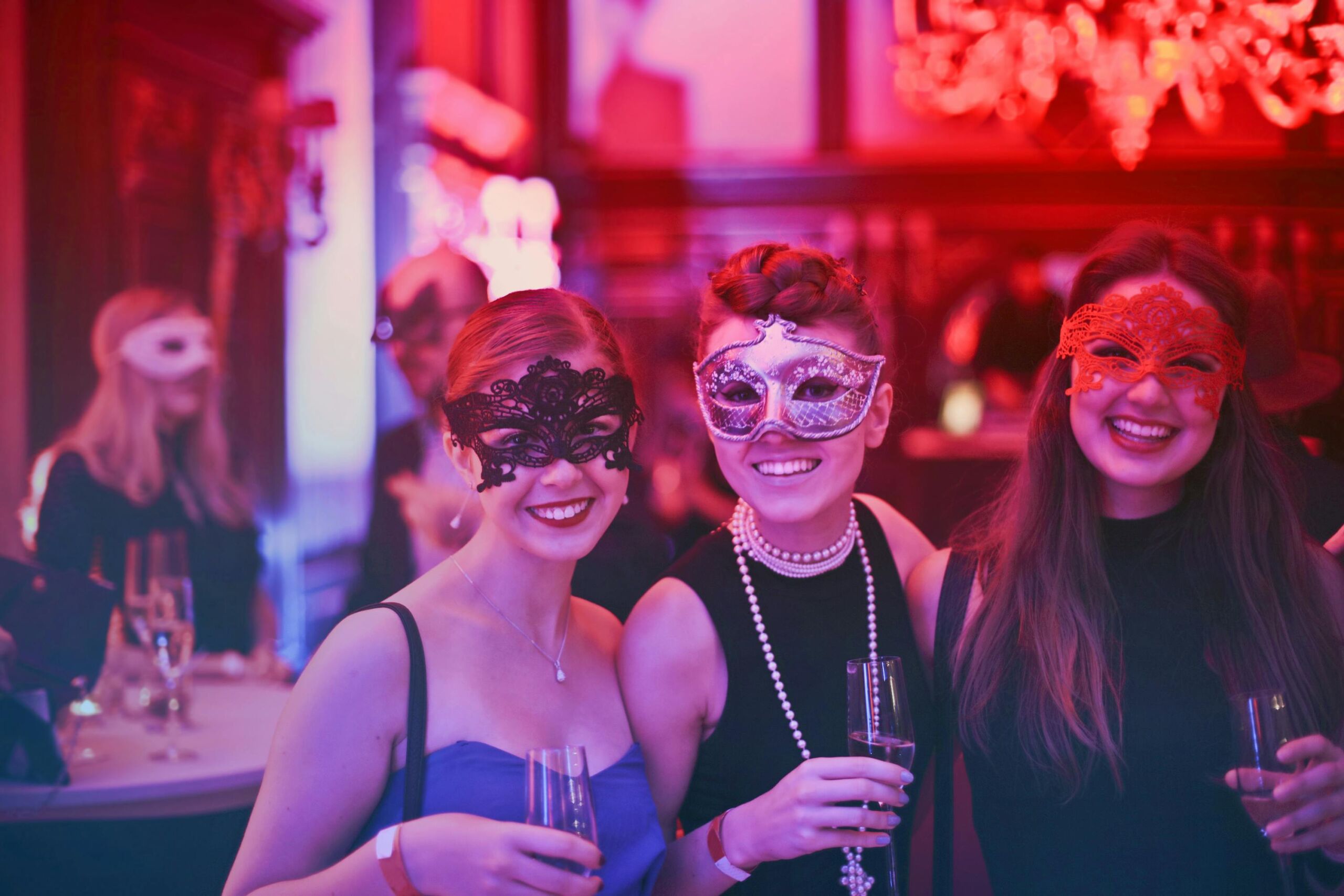3 women in masks taking a picture at a party.