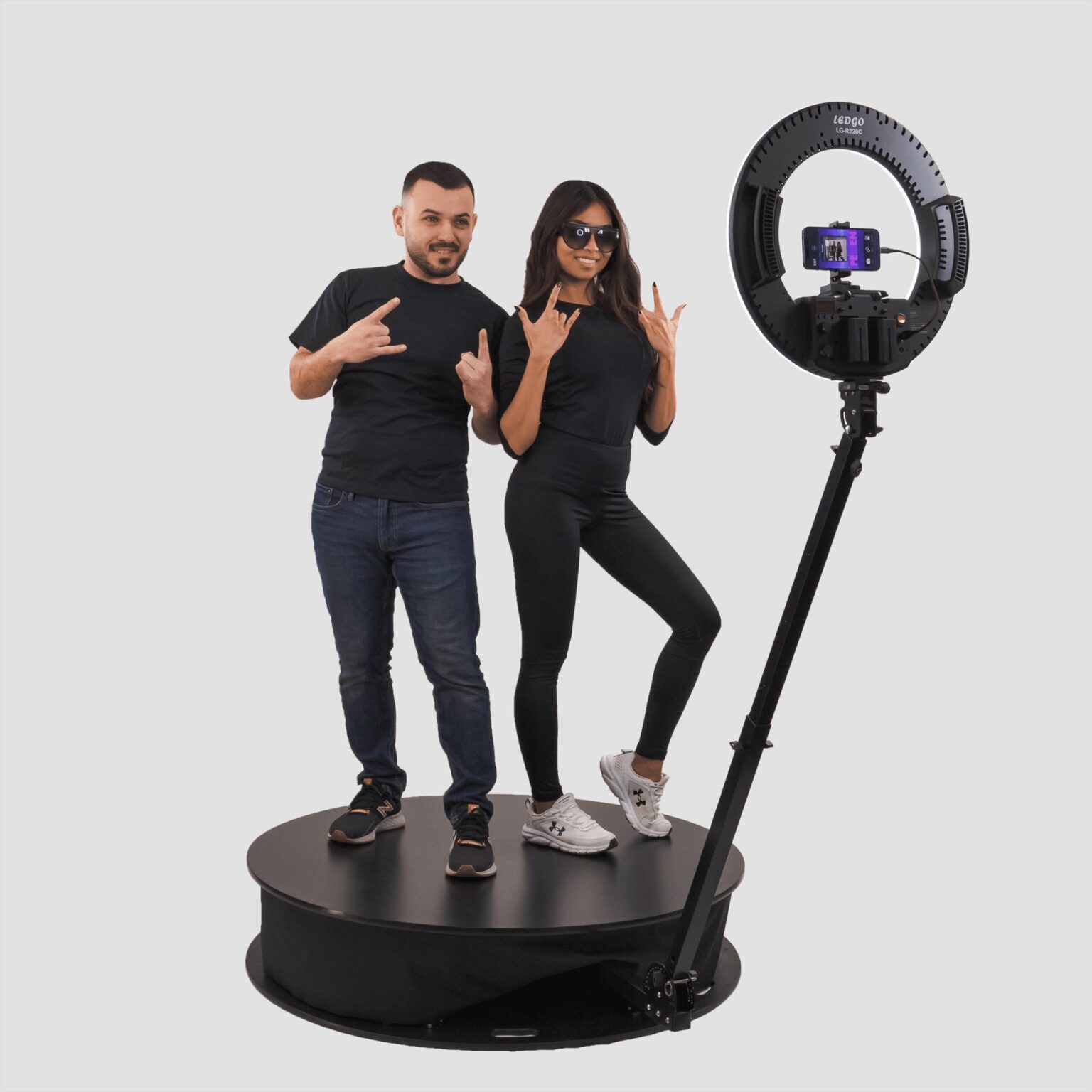 Two guests posing on the platform of a Motion 360 photo booth with the camera arm extended