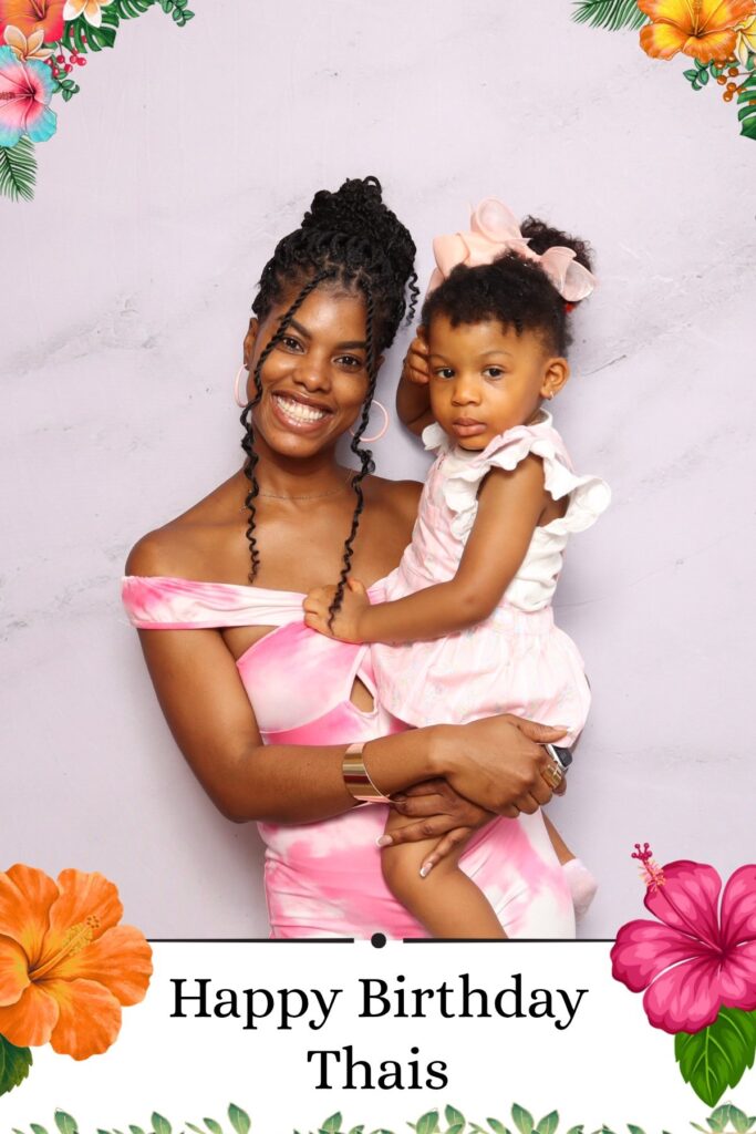 Mother and baby posing at a tropical themed birthday party photo booth