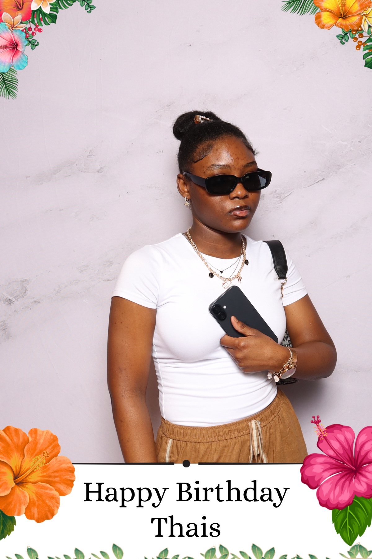 Guest in sunglasses posing at a tropical themed birthday party photo booth