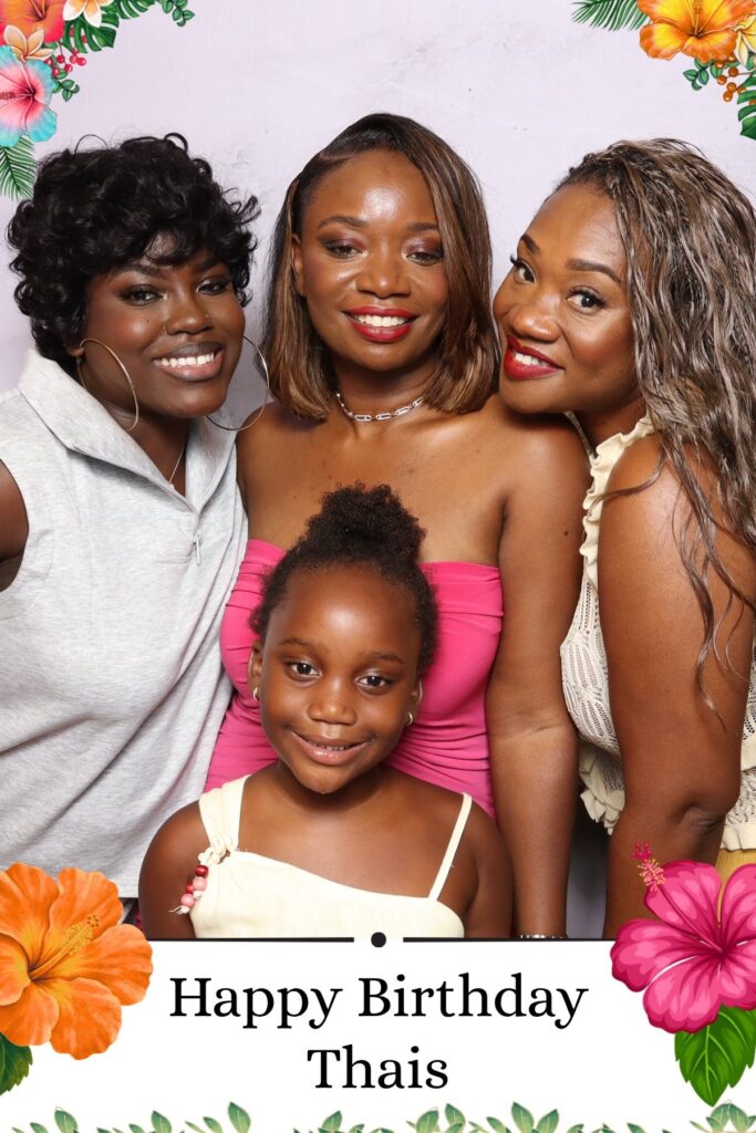 Four guests posing together at a tropical themed birthday party photo booth