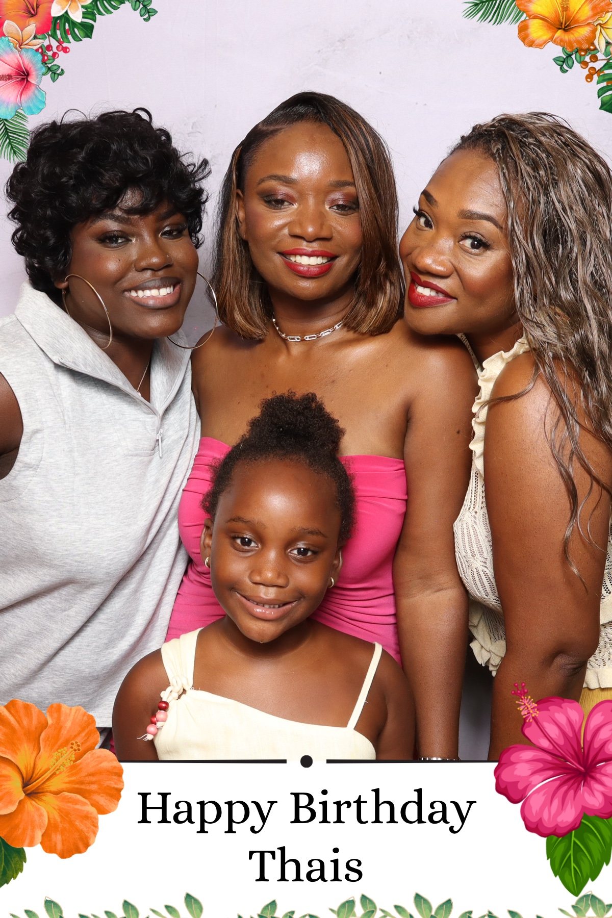 Four guests posing together at a tropical themed birthday party photo booth