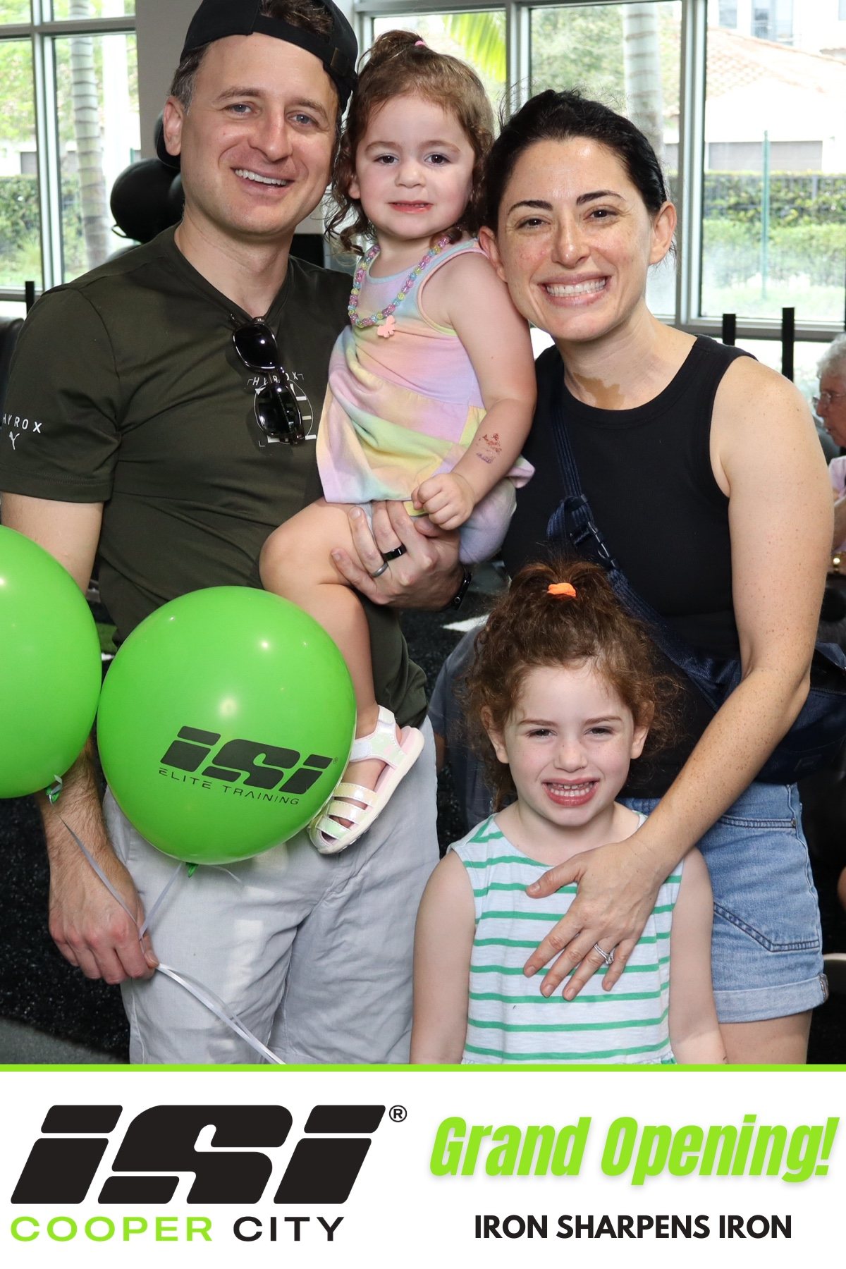 Family with two children holding balloons at a branded grand opening photo booth