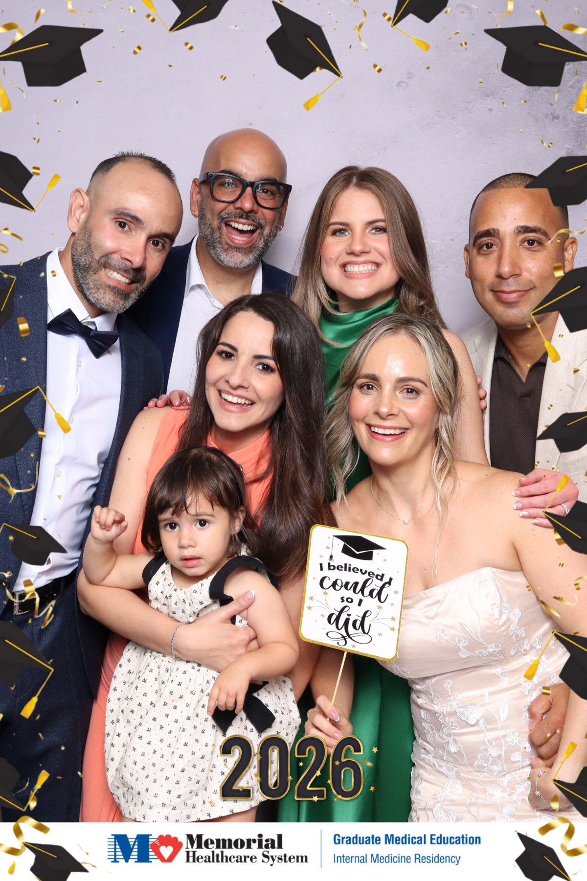 Large group including a child posing at a graduation photo booth