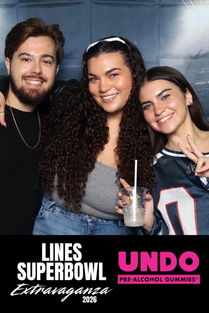 Three guests posing at a branded photo booth during a Super Bowl viewing activation